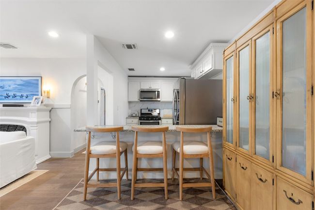 Kitchen featuring tasteful backsplash, a breakfast bar area, stainless steel appliances, and white cabinets | Image 11