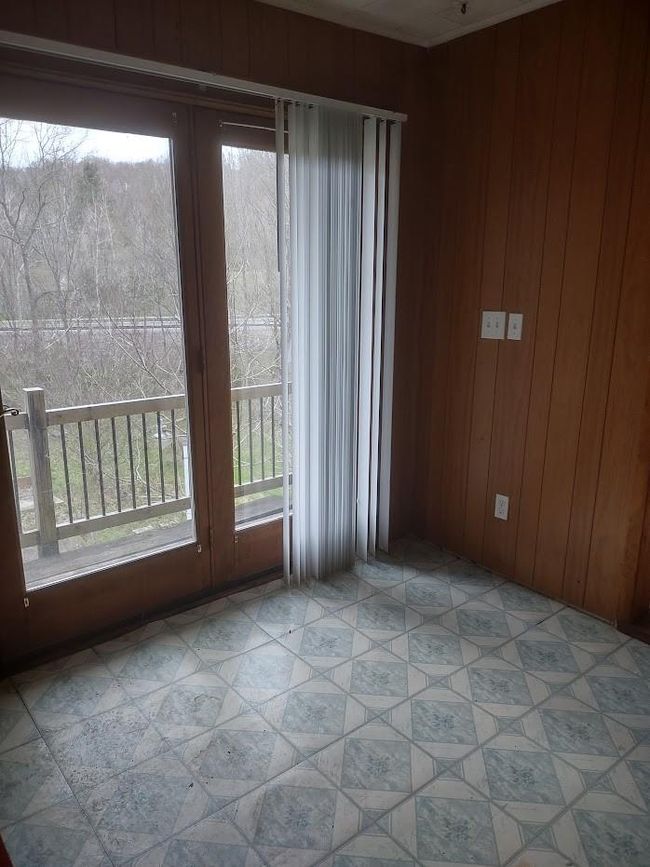 Unfurnished room featuring wooden walls, a healthy amount of sunlight, and light tile floors | Image 9
