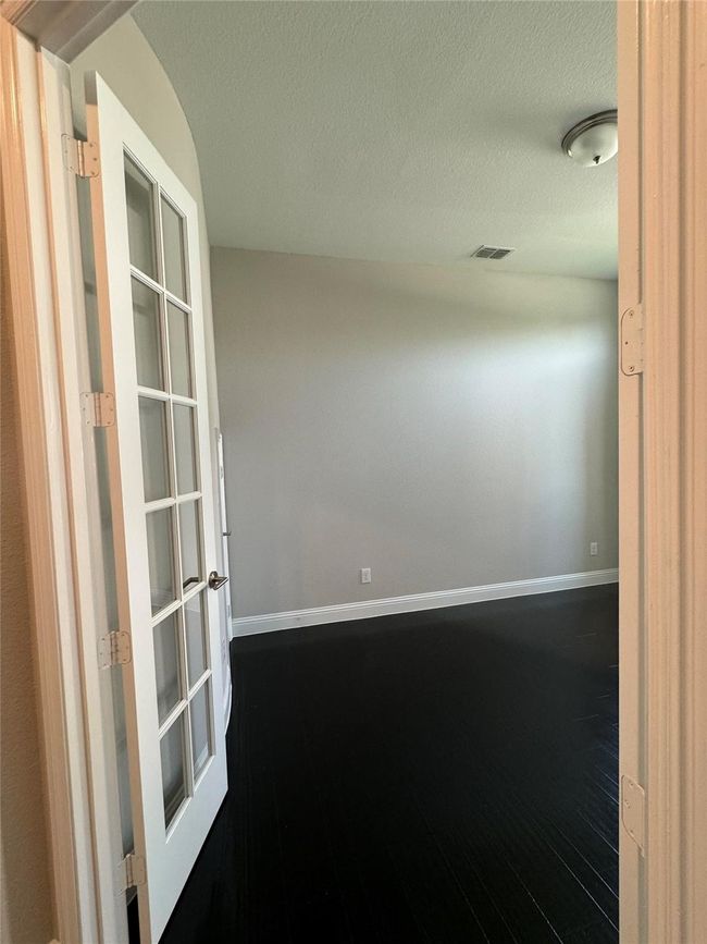 Unfurnished room with dark wood-type flooring, a textured ceiling, and french doors | Image 22