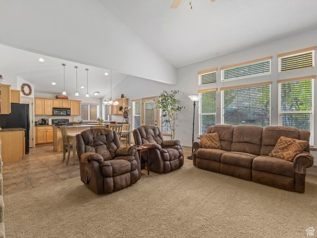 Living area with light carpet, a ceiling fan, a chandelier, recessed lighting, and high vaulted ceiling | Image 10