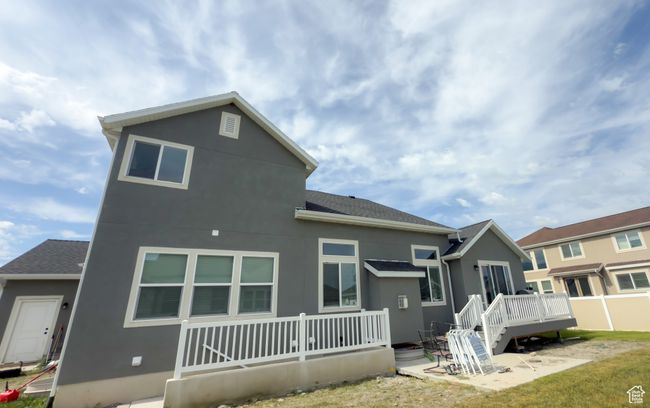 Rear view of property with a deck, stucco siding, roof with shingles, and a patio area | Image 27