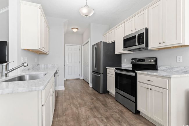 Kitchen with white cabinetry, appliances with stainless steel finishes, dark wood-style floors, and a sink | Image 12