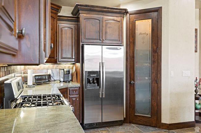 Kitchen featuring stainless steel appliances, backsplash, and dark stone finish flooring | Image 33