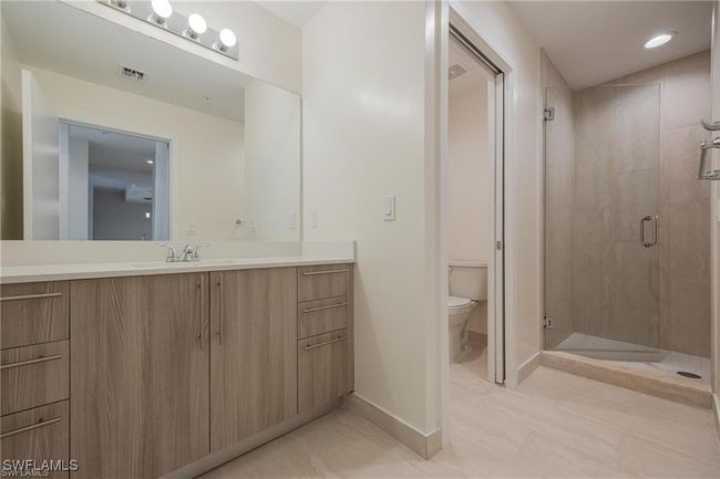 Bathroom with a shower stall, tile patterned floors, vanity, baseboards, and toilet | Image 9