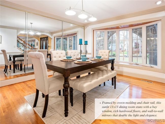 Framed by crown molding and chair rail, this sunlit 13x13 dining room stuns with a bay window, rich hardwood floors, and wall-to-wall mirrors that double the light and elegance. | Image 7
