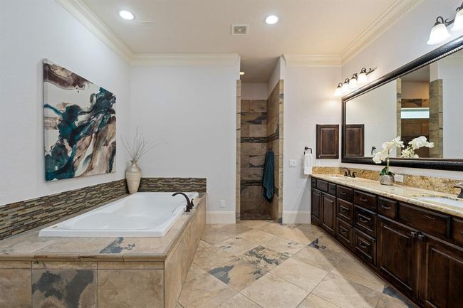 Relax and unwind in this spacious Primary Spa. The earthy tile flooring continues into the glass-free shower that includes dual shower heads, dual storage cubbies, a privacy window, and a large bench. | Image 28