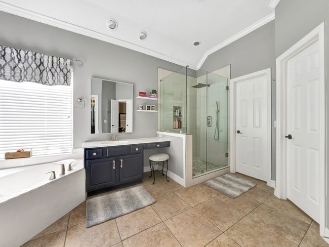 Full bath featuring a garden tub, sink vanity, a shower stall, tile floors, and crown molding | Image 28