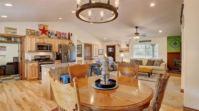 Dining space with light wood-type flooring, a chandelier, a ceiling fan, recessed lighting, and high vaulted ceiling | Image 14