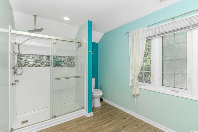 Bathroom featuring a shower stall, wood finished floors, lofted ceiling, and recessed lighting | Image 22