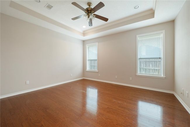 Spare room featuring a tray ceiling, crown molding, dark wood finished floors, ceiling fan, and recessed lighting | Image 17