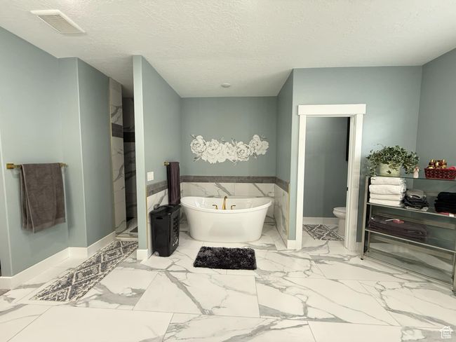 Full bath with toilet, a textured ceiling, marble finish floor, visible vents, and a freestanding bath | Image 41