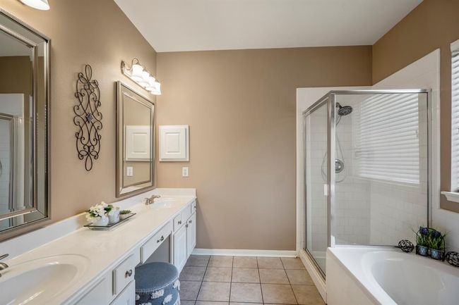 Entering the primary bath, you'll find double sinks on the left, with a vanity area in between for added convenience. On the right, a soaking tub sits beneath a window, while a separate shower completes the space. | Image 19
