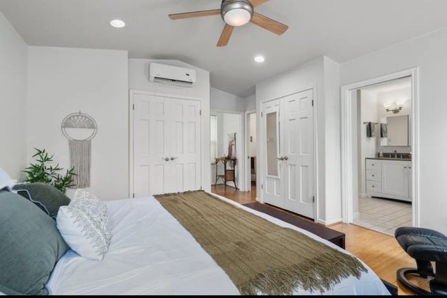 Bedroom with a wall mounted air conditioner, wood finished floors, vaulted ceiling, recessed lighting, and ensuite bath | Image 12