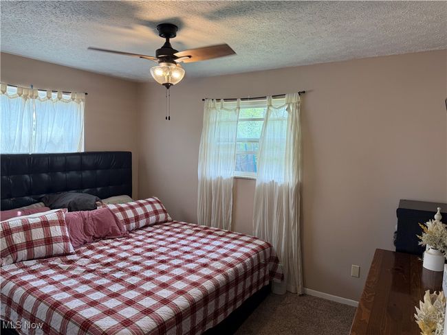 Bedroom with a ceiling fan, carpet, a textured ceiling, and multiple windows | Image 11