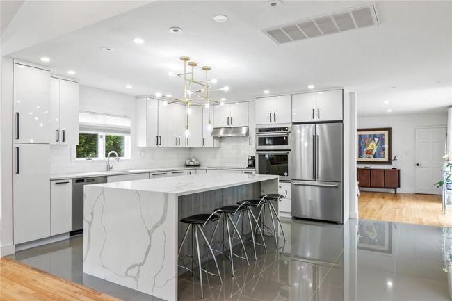Kitchen with stainless steel appliances, under cabinet range hood, modern cabinets, white cabinetry, and decorative backsplash | Image 7