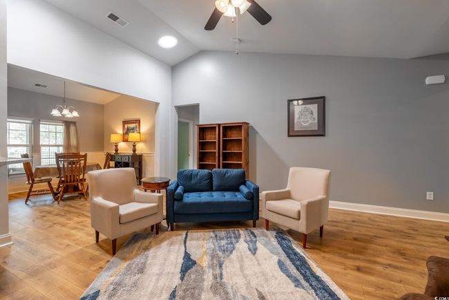 Living area featuring light wood-type flooring, ceiling fan with notable chandelier, and visible vents | Image 17