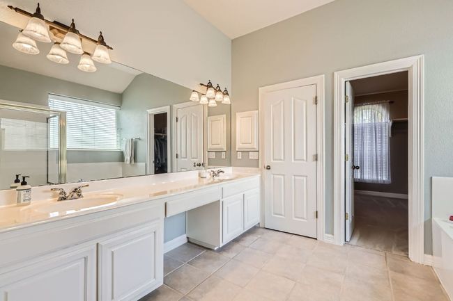 Ensuite bathroom featuring a spacious closet, double vanity, healthy amount of natural light, a shower stall, and lofted ceiling | Image 16