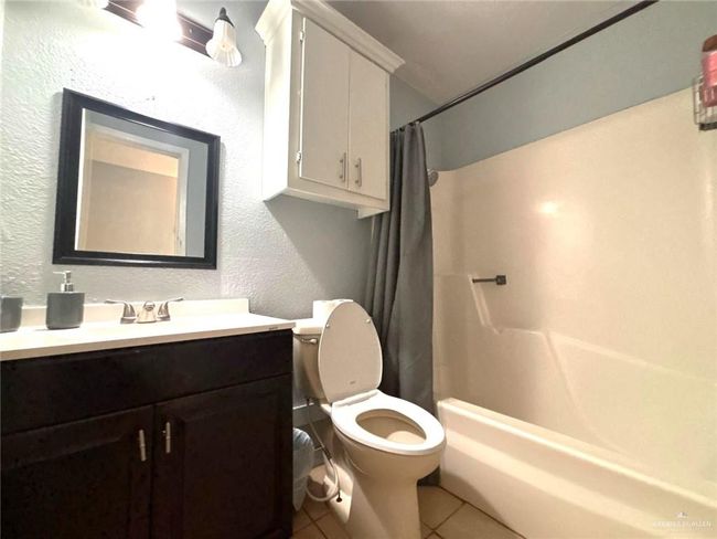 Bathroom featuring vanity, a textured wall, tile patterned flooring, shower / tub combo with curtain, and toilet | Image 13