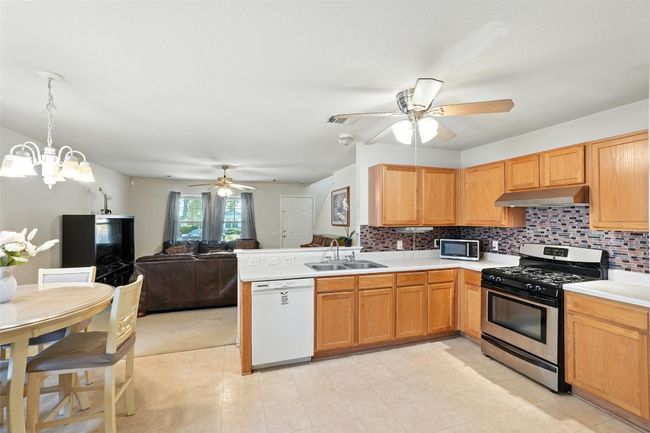 Kitchen featuring appliances with stainless steel finishes, open floor plan, ceiling fan, light countertops, and tasteful backsplash | Image 9
