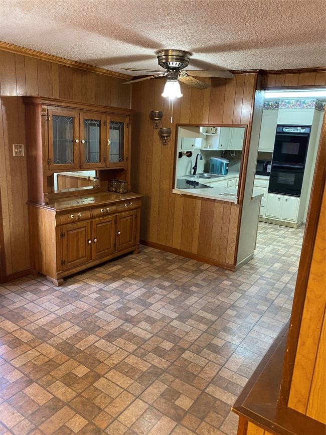 Kitchen featuring sink, a textured ceiling, wooden walls, and ceiling fan | Image 13