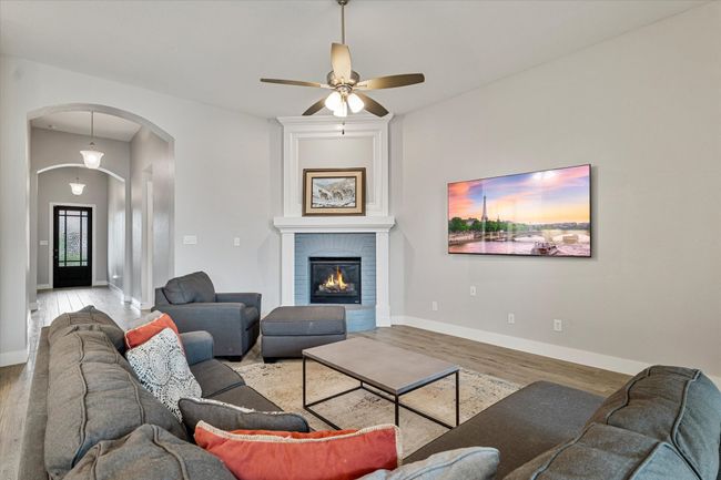 Living area featuring baseboards, arched walkways, a ceiling fan, and wood finished floors | Image 4