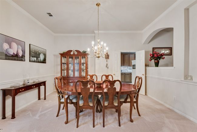 Dining room with ornamental molding, light carpet, a chandelier, and baseboards | Image 18