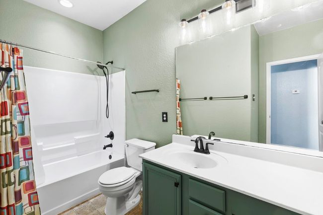Bathroom featuring a textured wall, vanity, shower / tub combo, and tile patterned flooring | Image 25