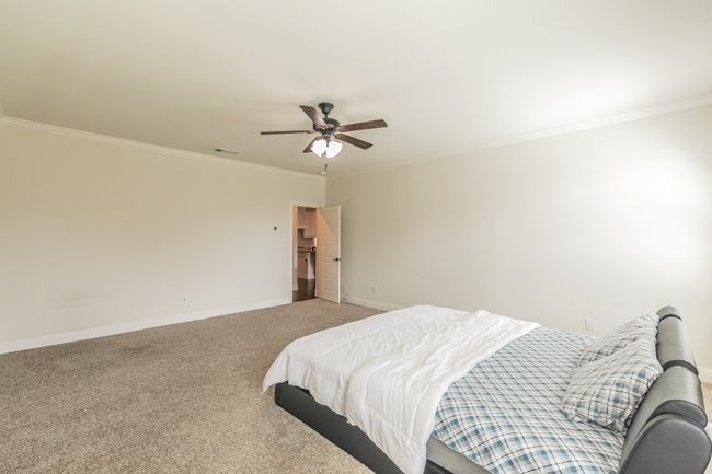 Bedroom with visible vents, crown molding, baseboards, light colored carpet, and ceiling fan | Image 28