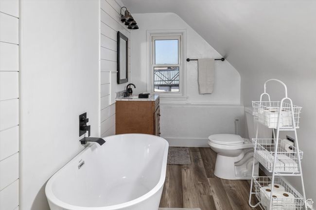 Bathroom with wood-type flooring, vanity, a bathtub, toilet, and vaulted ceiling | Image 26