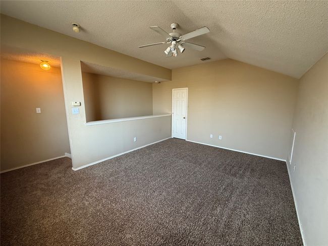 Unfurnished room with ceiling fan, vaulted ceiling, dark carpet, a textured ceiling, and baseboards | Image 29
