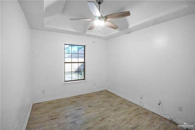 Unfurnished room with a raised ceiling, a ceiling fan, and wood finished floors | Image 7