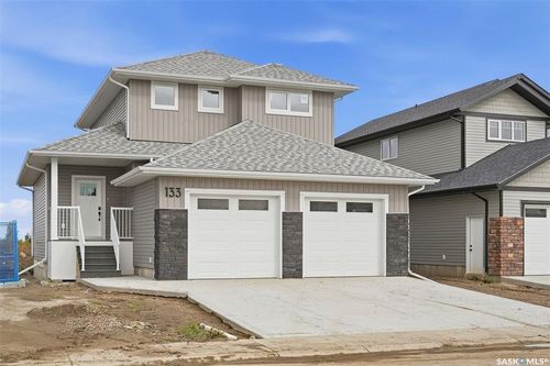 Two-story residence featuring light gray vertical siding and a dark gray shingled roof | Card Image