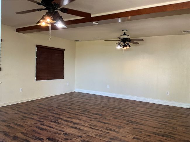 Empty room with dark wood-style flooring, baseboards, ceiling fan, and visible vents | Image 10