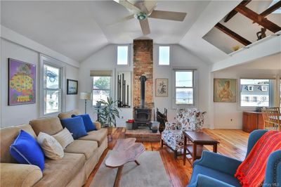 Living room with a wood stove, ceiling fan, original 1800s wide board floors floors, and vaulted ceiling | Image 3