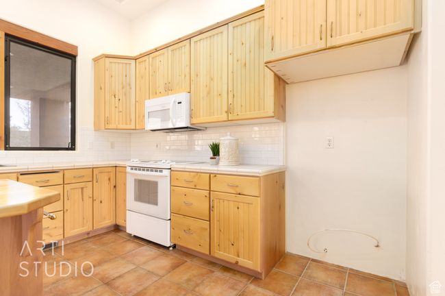 Kitchen with light brown cabinets, decorative backsplash, tile counters, and white appliances | Image 21