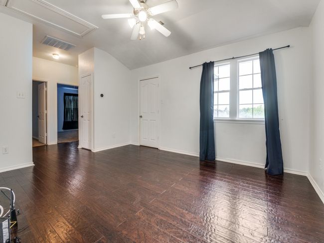 Empty room with attic access, a ceiling fan, visible vents, vaulted ceiling, and hardwood / wood-style flooring | Image 12