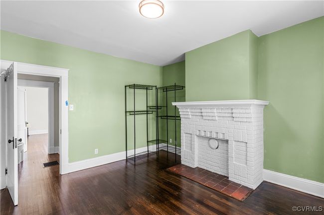 Unfurnished living room featuring a fireplace, visible vents, baseboards, and dark wood-style floors | Image 24