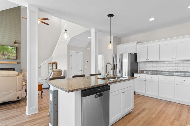 Kitchen featuring appliances with stainless steel finishes, light wood-style flooring, dark stone counters, tasteful backsplash, and white cabinetry | Image 12