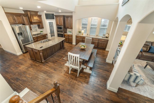 Kitchen featuring appliances with stainless steel finishes, a sink, arched walkways, a center island with sink, and light stone counters | Image 11