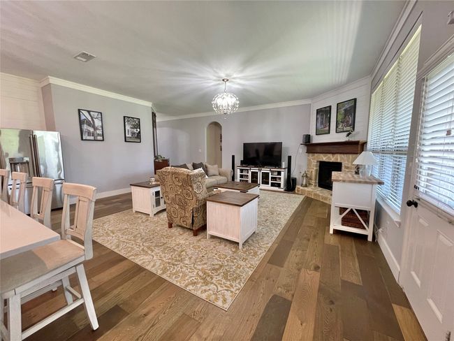 Living area with arched walkways, dark wood-style flooring, crown molding, baseboards, and a fireplace | Image 17