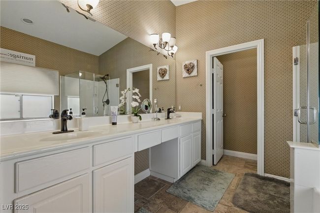 Full bath featuring a sink, walk in shower, double vanity, a notable chandelier, and stone finish floor | Image 22