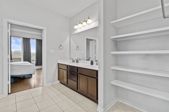 Ensuite bathroom featuring tile patterned flooring, double vanity, and built in storage shelves. | Image 21