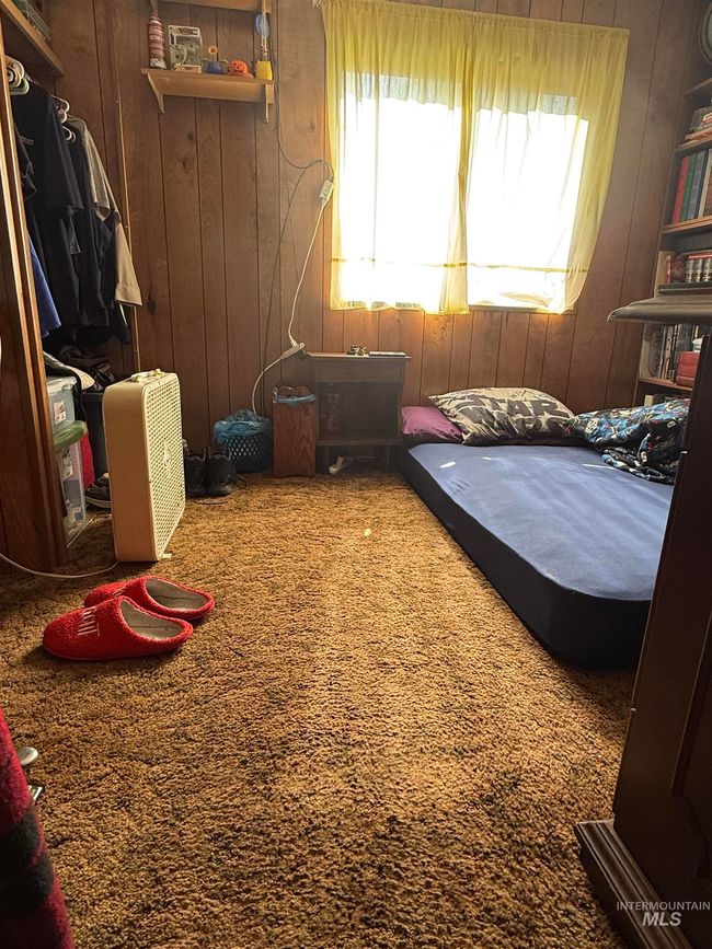 Bedroom with multiple windows, wooden walls, and carpet flooring | Image 13