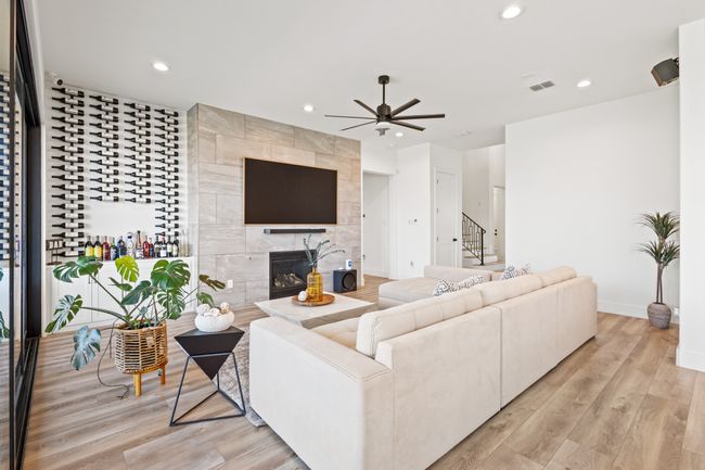 Living area featuring a ceiling fan, recessed lighting, stairway, a tiled fireplace, and light wood-style floors | Image 11