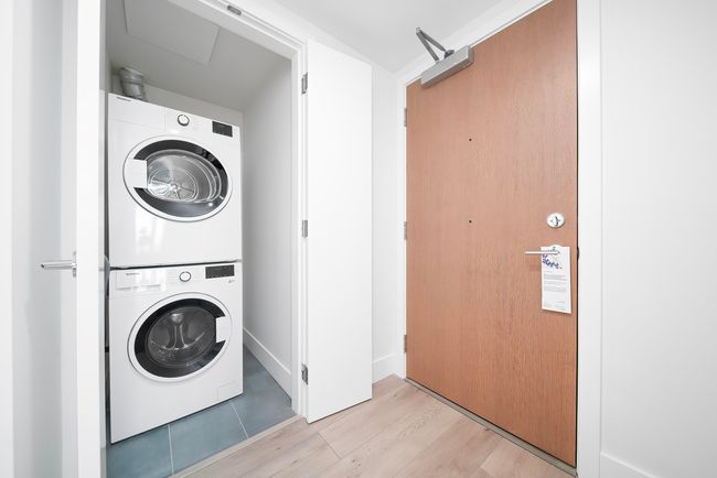 Laundry area with light wood-type flooring, stacked washing maching and dryer, and laundry area | Image 10