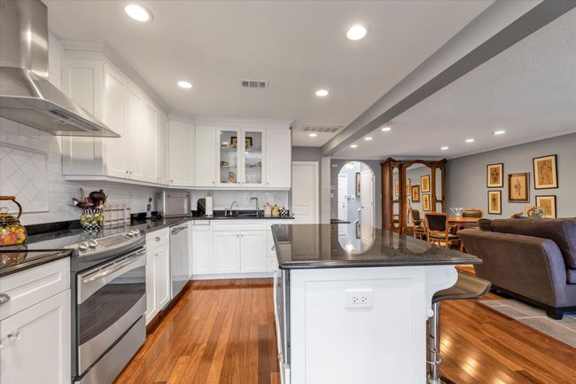 Kitchen with open floor plan, wall chimney exhaust hood, visible vents, and stainless steel appliances | Image 8