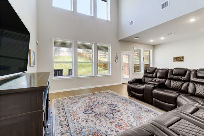 Living area featuring plenty of natural light, a high ceiling, wood finished floors, and baseboards | Image 7