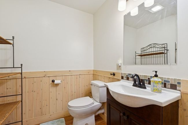 Recently added Half Bath with toilet, vanity, a wainscoted wall, and wood finished floors. Lower Level. | Image 67