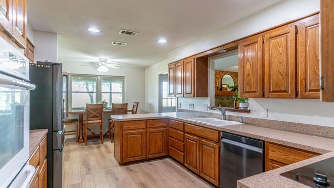 Kitchen featuring brown cabinetry, appliances with stainless steel finishes, a sink, and visible vents | Image 11