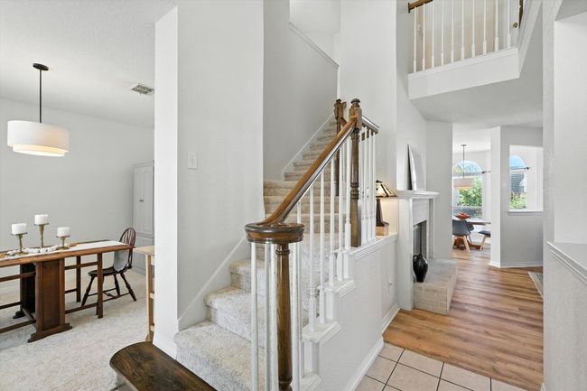 Stairway with tile patterned flooring, a high ceiling, and a brick fireplace | Image 7